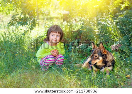 Happy little girl playing with big dog in the garden