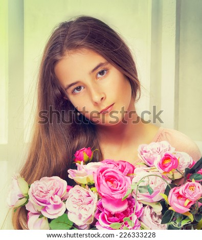Portrait of beautiful young girl with long brown hair and flowers