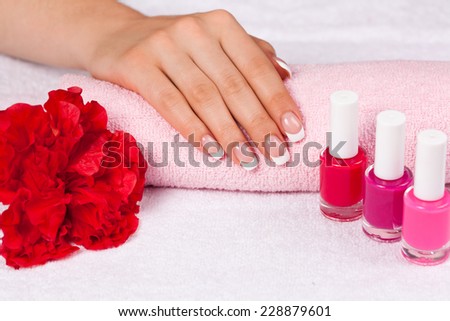 Beautiful woman\'s hand with perfect french manicure on towel decorated wit flower and nail polish