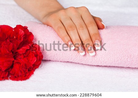 Beautiful woman\'s hand with perfect french manicure on towel decorated wit flower