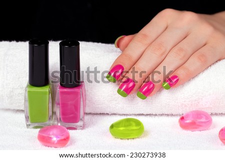 Beautiful woman\'s hand with two-color manicure on white towel on black background