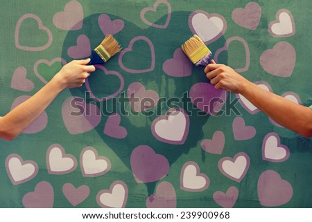 Young man and woman painting hearts on the concrete wall