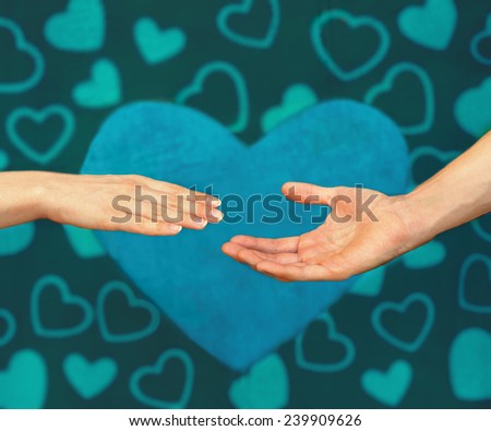 Male hand reaches for the female hand against hearts painted background