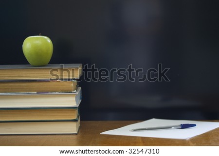 School books with apple on desk.