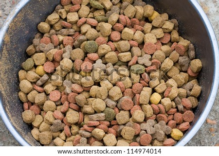 Dry dog food contained in a metal bowl. Closeup image of different coloured dry dog food.