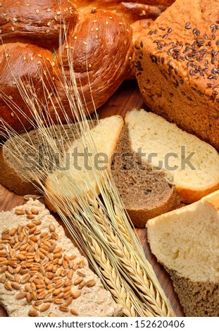 Fresh bread, wheat ears, wheat grains on the wooden background