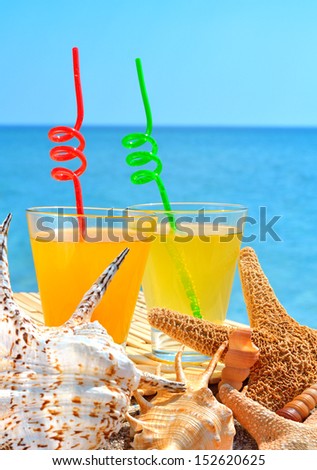 Starfish, shells and two glasses of orange cocktail against the blue sea
