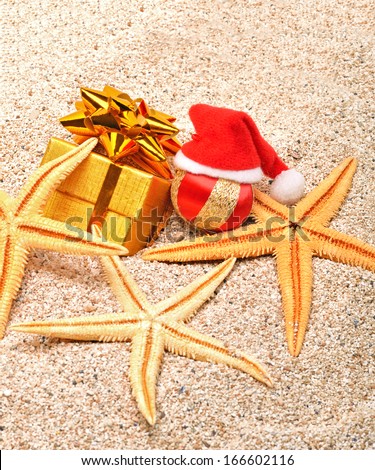 Starfishes, christmas bauble and a gift box on the sand