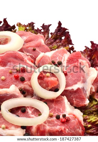Raw meet pieces with sliced onion and black pepper isolated on white