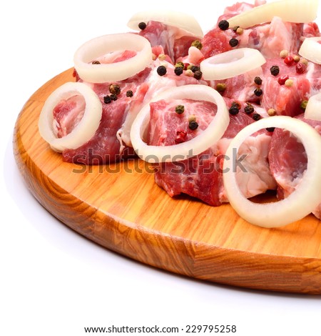 Raw meet pieces, sliced onion and black pepper on the board isolated on white