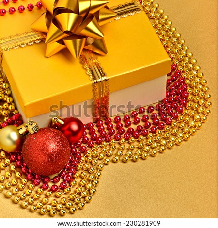 Yellow gift box with christmas baubles and beads around
