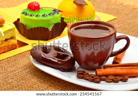 Different cakes, cup of coffee, cinnamon sticks and chocolate cookies on white plate on sacking background