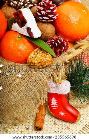 Christmas tangerines walnuts, pine cones, nougat, christmas balls, pine twig and brittle candies on christmas sacking background
