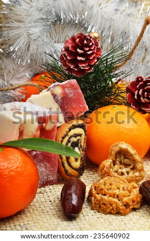 Christmas tangerines, sweet delights, pine cones, cookies and brittle candies on tinsel background