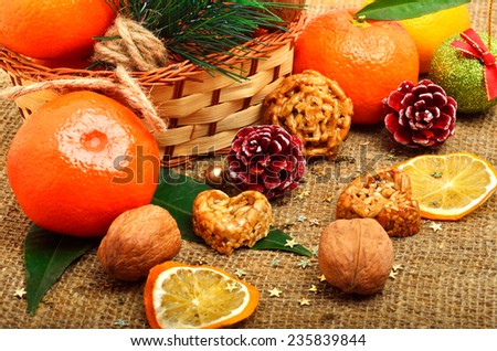 Christmas tangerines with dried lemon, walnuts, pinecone and brittle candies on christmas sacking background