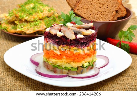 Russian traditional herring salad with beetroot, carrot, eggs on white pllate. Bread and cutlets