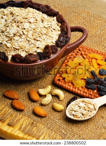 Oatmeal in ceramic plate, spoon, raisins, cashews and almonds.