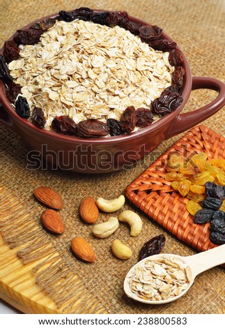 Oatmeal in ceramic plate, spoon, raisins, cashews and almonds.