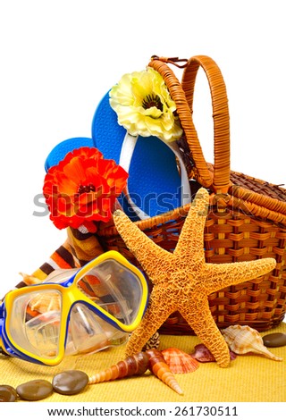 Wicker basket, flip-flops, fishstar, goggles on the towel isolated on white