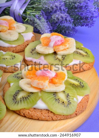 Fruit dessert with exotic fruits and lavender flowers on a wooden background