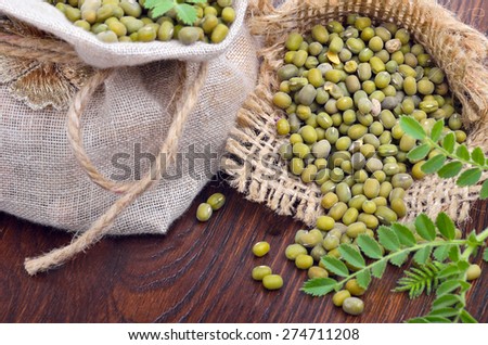 Chickpea varieties in a burlap bag with green sprouts on a wooden background