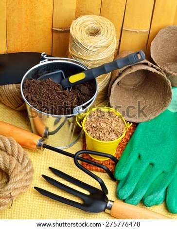 gardening tools, peat cups, thread; seeds in tins against wooden fence