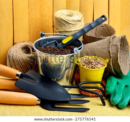 gardening tools, peat cups, thread; seeds in tins against wooden fence