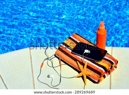 bath towels, sun spray, cell phone, starfish near the swimming pool