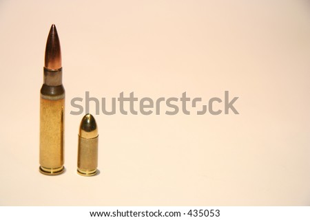A rifle shot and a 9mm pistol bullet standing next to each other.