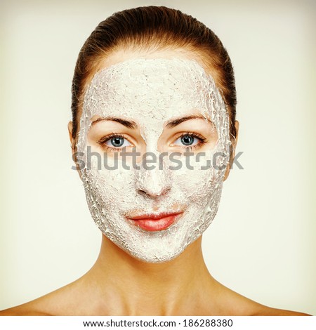 Young emotional woman with facial mask smiling
