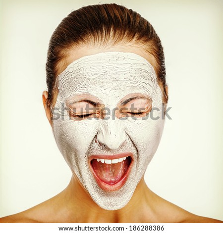 Young emotional woman with facial mask screaming
