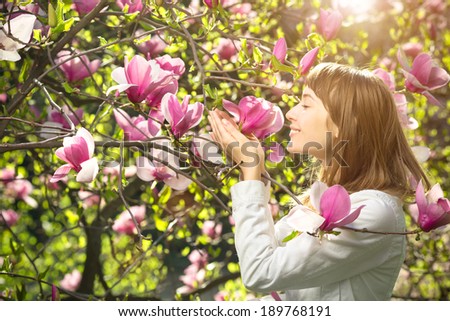 Woman in spring. Young beautiful woman enjoying spring sunny morning near the blooming magnolia tree. Natural beauty spring concept.