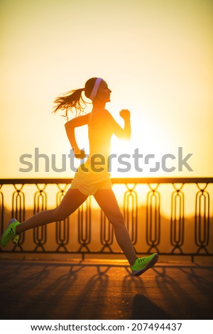 Running woman. Runner is jogging in sunny bright light on sunrise. Female fitness model training outside in the city on a quay. Sport lifestyle.