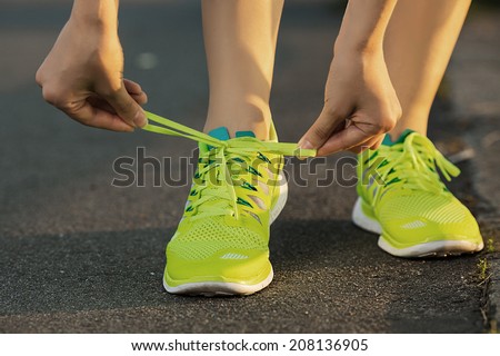 Running shoes. Barefoot running shoes closeup. Female athlete tying laces for jogging on road in minimalistic barefoot running shoes. Runner getting ready for training. Sport lifestyle.