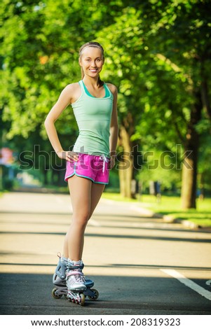 Rollerblading woman. Young attractive female fitness model is having fun skating in a city park in the sunny morning. Sports lifestyle concept.
