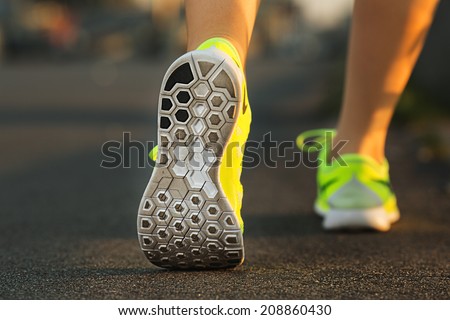 Runner woman feet running on road closeup on shoe. Female fitness model sunrise jog workout. Sports healthy lifestyle concept.