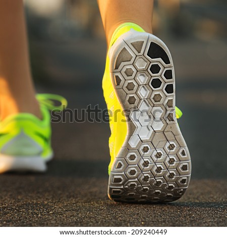 Runner woman feet running on road closeup on shoe. Female fitness model sunrise jog workout. Sports healthy lifestyle concept.