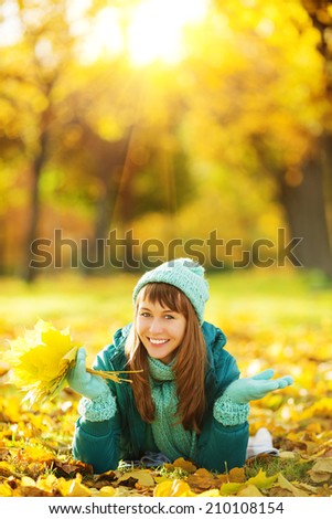 Beautiful happy young woman in the autumn park. Joyful woman wearing bright teal hat and scarf is having fun outdoors in a bright yellow trees. Colorful fall concept.