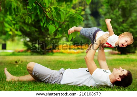 Happy father and son playing together having fun in the green summer park on a warm sunny day. Family and love concept.