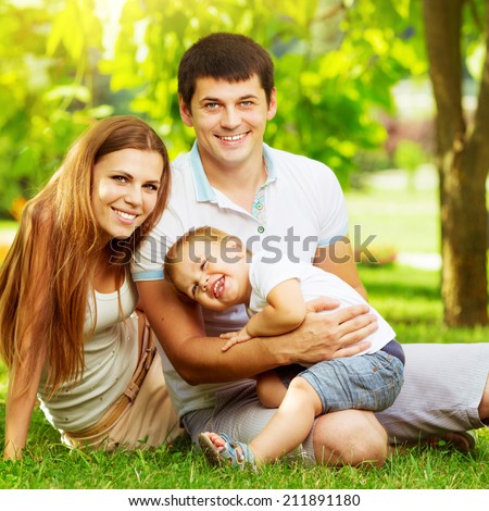 Happy young family is having fun in the green summer park outdoors on a sunny day.