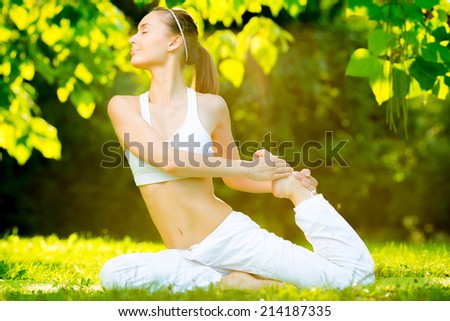 Yoga outdoors. Young healthy beautiful woman is doing a yoga asana in the green park. Concept of healthy lifestyle and relaxation