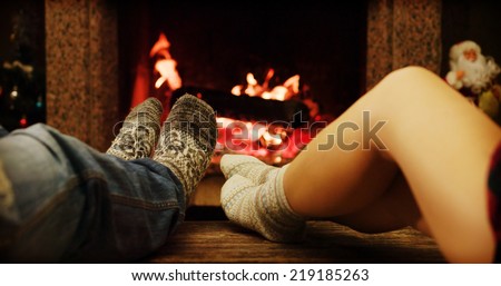 Feet in woolen socks warming by cozy fire in Christmas time in slow motion. Family couple warming their feet by the fireplace in winter time.