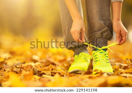 Running shoes. Barefoot running shoes closeup. Female athlete tying laces for jogging on autumn road in minimalistic barefoot running shoes. Runner getting ready for training in fall. Sport lifestyle