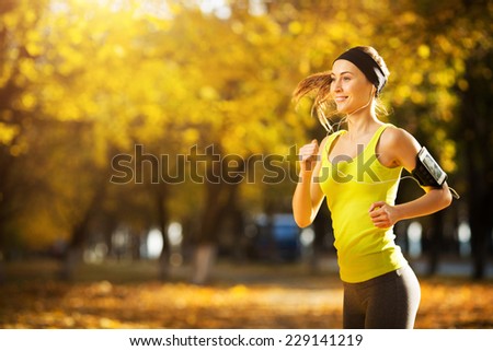 Female fitness model training outside on a warm fall day and listening to music. Sport lifestyle.