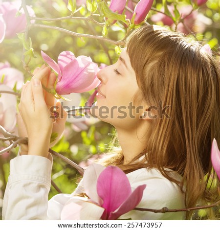 Woman in spring blossom. Young naturally beautiful woman near the magnolia blooming tree in spring time. Eco beauty and health concept.