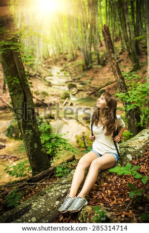 Hiking woman exploring mountain canyon with a river. Young sportive woman wondering in the sunny mountain forest.