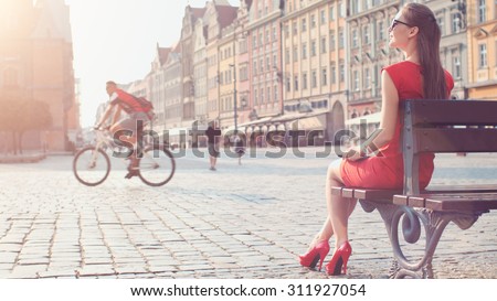 Sexy Business Woman using digital tablet. Slow Motion. Beautiful woman in red high-heeled shoes and dress enjoying sunny morning in the city, browsing Internet. Lens Flare.