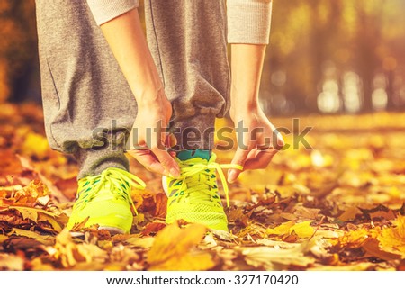 Running shoes. Barefoot running shoes closeup. Female athlete tying laces for jogging on autumn road in minimalistic barefoot running shoes. Runner getting ready for training in fall. Sport lifestyle