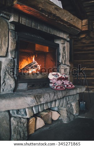 Christmas comfortable slippers by the warm cozy fireplace. Relaxing atmosphere in a chalet by authentic vintage fireside. Winter and Christmas holidays concept.