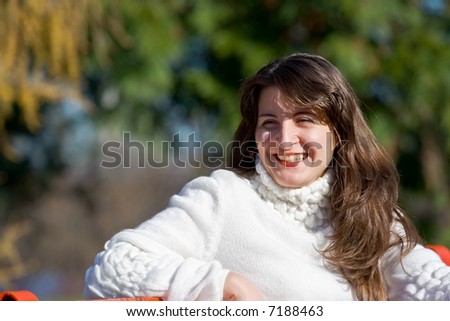 Pretty young woman sitting on a bench in a park and laughing